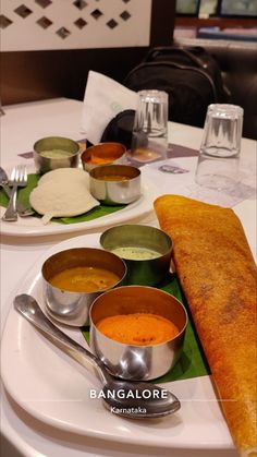 two plates filled with different types of soups on top of a white tablecloth