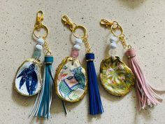 four different key chains with tassels on them sitting on a counter next to each other