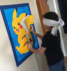 a young boy holding a pair of scissors in front of a paper cut out of a pikachu