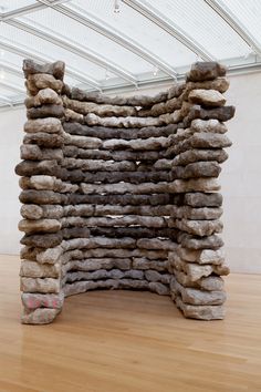 a large stack of rocks sitting on top of a hard wood floor next to a white wall