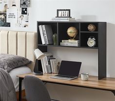 a laptop computer sitting on top of a wooden desk next to a book shelf filled with books