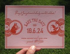 a person holding up a pink save the date card in their hand on some green grass