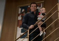 a man holding a baby on top of a stair case