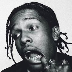 a black and white photo of a man with dreadlocks holding his finger to his mouth