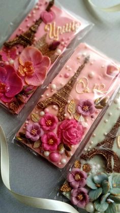 three decorated cell phones sitting on top of a table next to a ribbon and some flowers