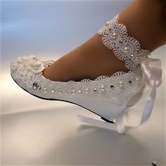 a close up of a person's foot wearing white shoes with lace and pearls