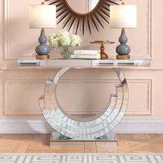 a console table with two lamps and a mirror on the wall in front of it