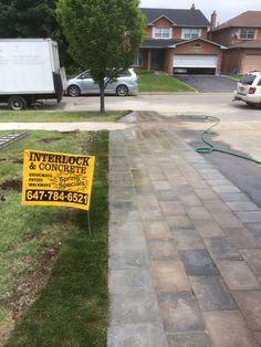 a yellow sign sitting on the side of a road next to a grass covered sidewalk