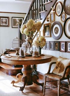 a dining room table with chairs and pictures on the wall in front of it's staircase