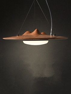 a wooden light fixture hanging from the ceiling in a dark room with mountains on it