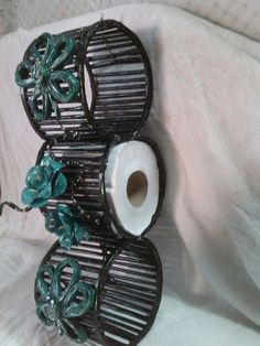 two toilet paper holders with flowers on them sitting on a white cloth covered bed sheet