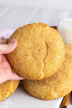 a person holding a cookie in front of some cinnamon sticks