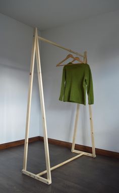 a clothes rack with a green sweater hanging on it's hangers in an empty room