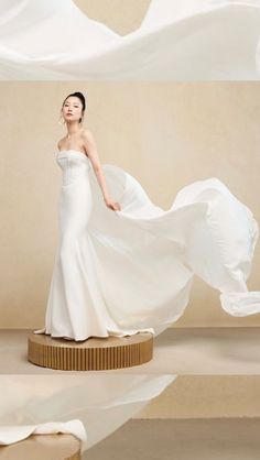 a woman in a white dress is standing on a round platform with her flowing fabric behind her