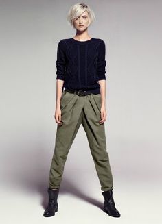 a woman in black sweater and khaki pants posing for a photo with her hands on her hips