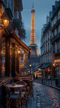 the eiffel tower is lit up at night, with tables and chairs outside