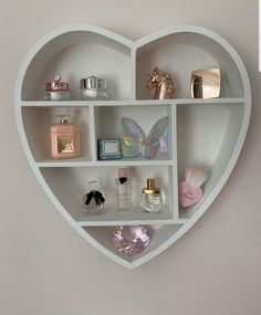 a heart shaped shelf filled with different types of perfumes and other items on top of it