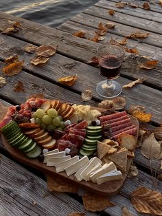 a wooden table topped with lots of different types of food and wine glasses on top of it