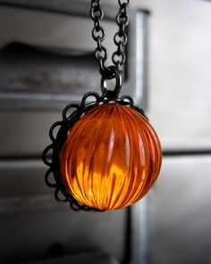 an orange glass ball hanging from a black chain