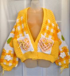 a crocheted yellow sweater with flowers on it