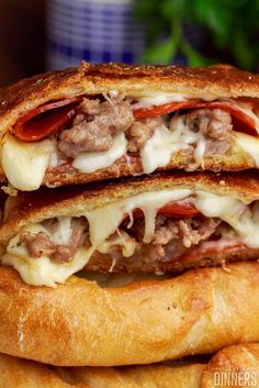 two sandwiches stacked on top of each other with meat, cheese and sauces in between them