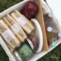 an open container filled with food on top of a grass covered field next to apples