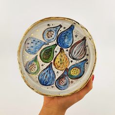 a hand holding a decorative plate with blue, green and yellow designs on the outside