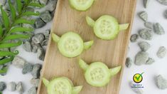 cucumbers cut into small pieces on a wooden cutting board next to rocks and leaves