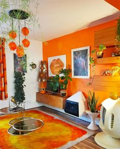 an orange living room with potted plants on the wall and pictures hanging above it