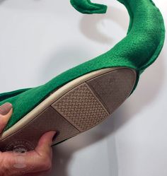 a person is holding up a green shoe