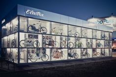 an illuminated display case with bicycles on the front and side walls at night, lit up by street lights