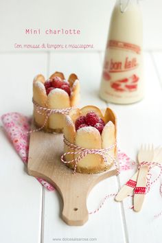 mini charlottes with raspberries and cream on a cutting board next to a bottle of milk