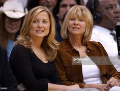 two women sitting next to each other in front of an audience at a basketball game