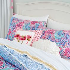 a white bed topped with lots of colorful pillows