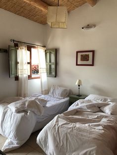 there are two beds in the room with white sheets and blankets on top of them