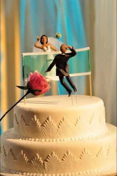 two figurines on top of a wedding cake, one is holding a rose