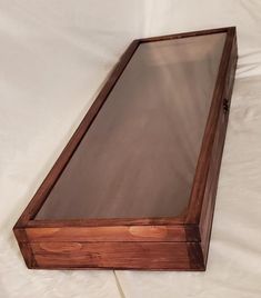 a wooden box with glass inside sitting on a white sheet