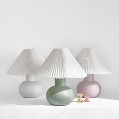 three different colored lamps sitting on top of a white table next to eachother