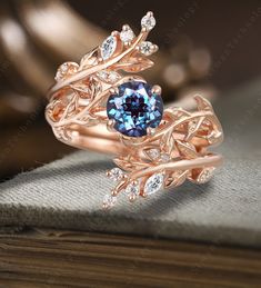 a blue diamond ring sitting on top of a wooden table next to an open book