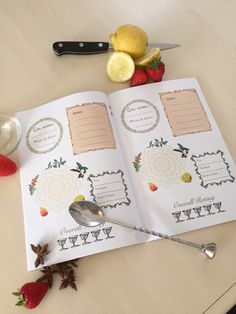 an open recipe book sitting on top of a table next to strawberries and lemons