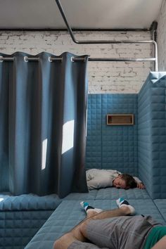 a man laying on top of a bed in a room with blue walls and curtains