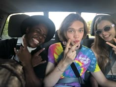 three people sitting in the back seat of a car with their hands on their lips