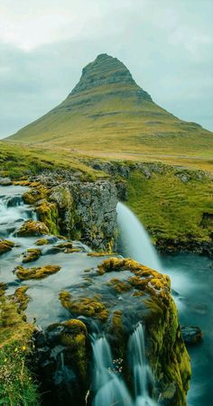 there is a small waterfall in the middle of this field with moss growing on it