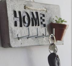 a metal key holder with a house sign on it and a potted plant hanging from the hook