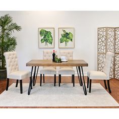 a dining room table with white chairs and a rug on the floor in front of it