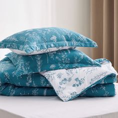 a stack of pillows sitting on top of a bed covered in blue and white sheets