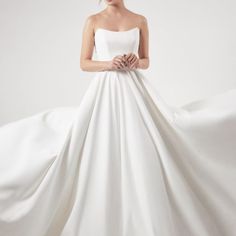 a woman in a white wedding dress with her hands on her hips and the skirt flowing