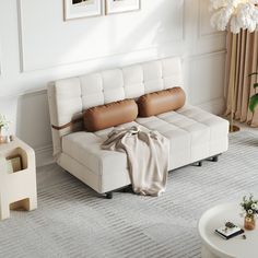 a living room with a white couch and brown leather pillows on the back of it