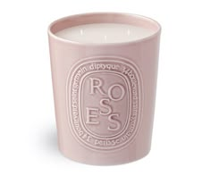 a pink candle that is sitting on a white surface with the words roses printed on it