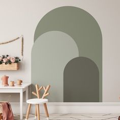 a living room with a white table and chair in front of a wall mural that looks like an arch